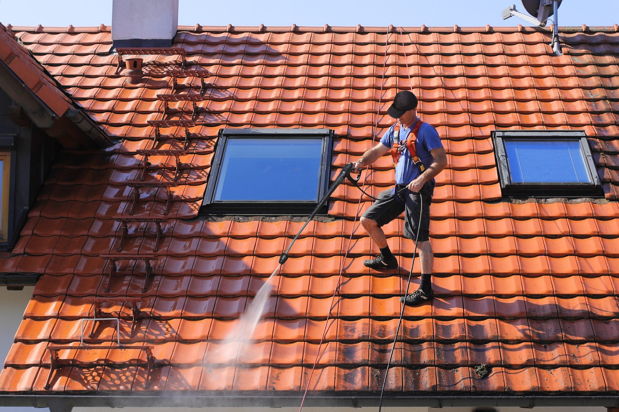 Worker is cleaning the roof and rainwater gutter with high pressure.