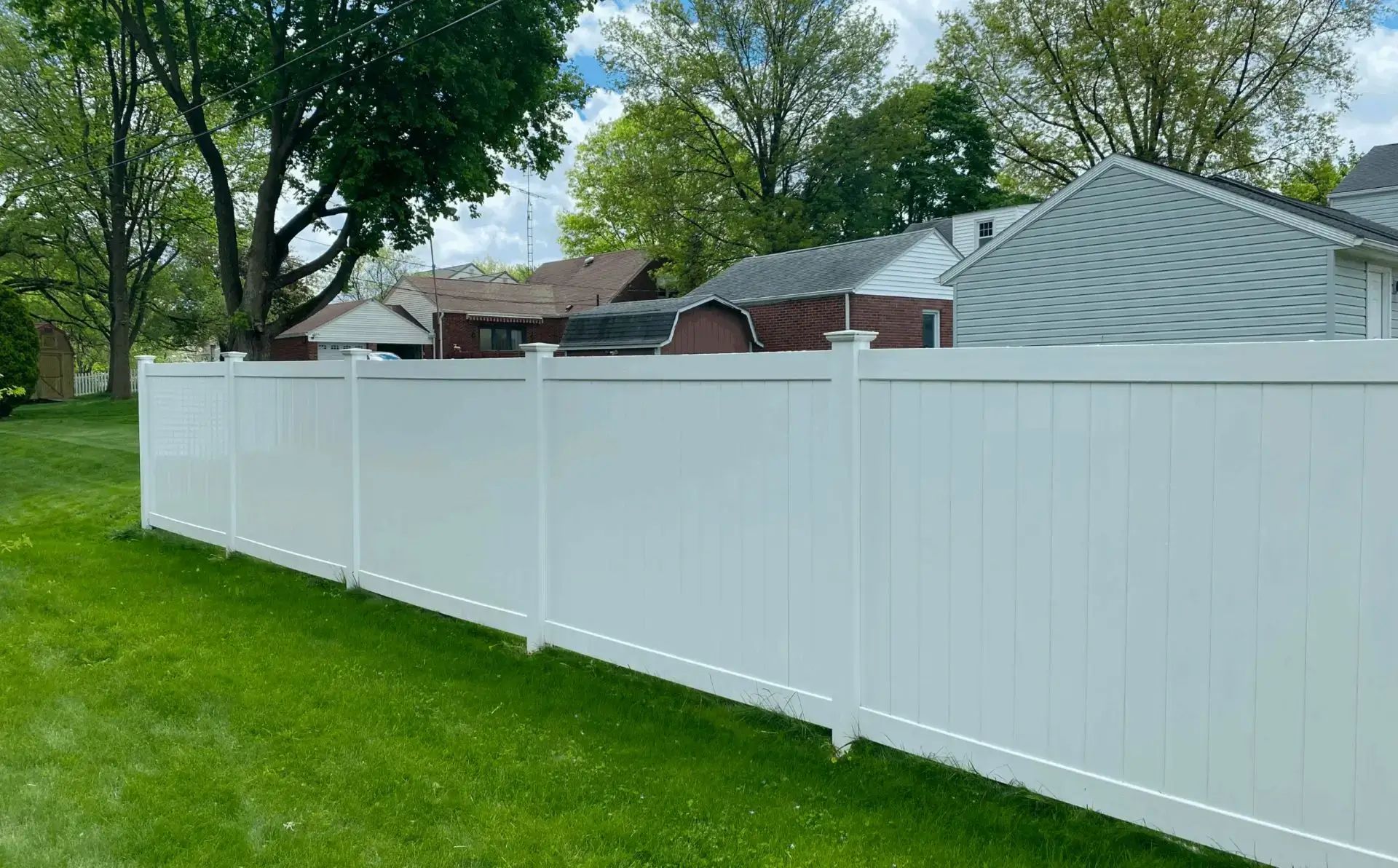 White fence with grass and trees background.
