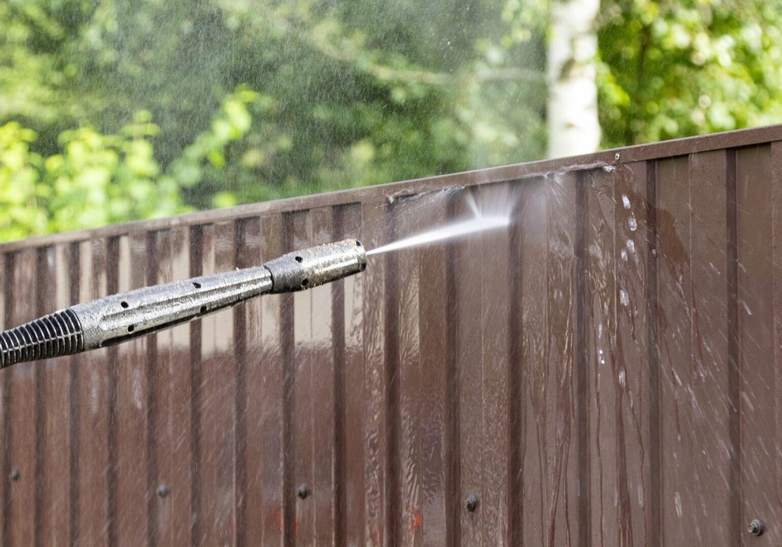 Cleaning fence with high pressure power washer, cleaning dirty wall.